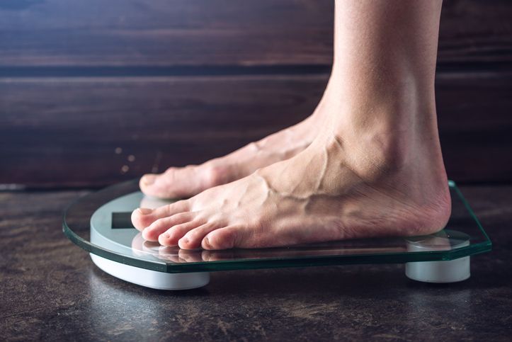 Female-feet-standing-on-electronic-scales-for-weight-control-on-dark-background.-Concept-of-sports-training,-diets-959543086_727x485